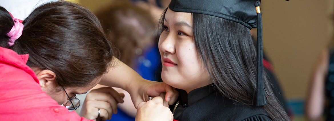A student getting their graduation gown pinned