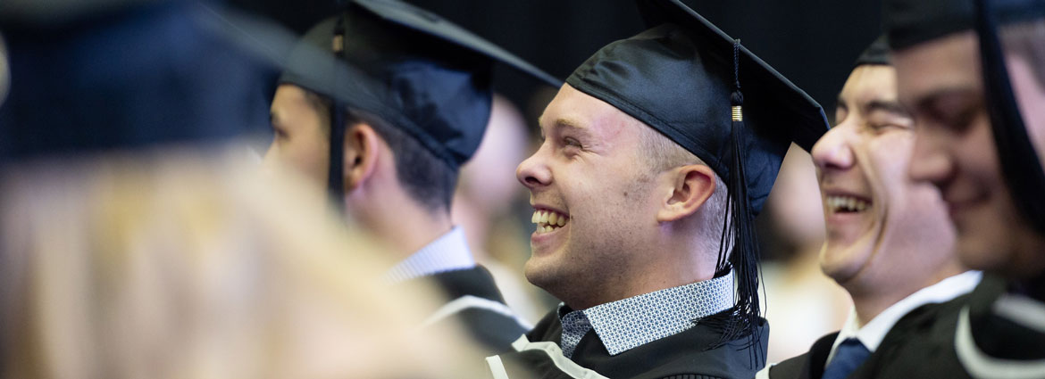 A graduate smiling and laughing while watching the ceremony