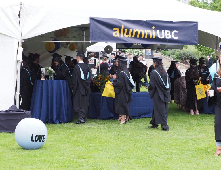 Picture includes an Alumni UBC tent with students in regalia walking around